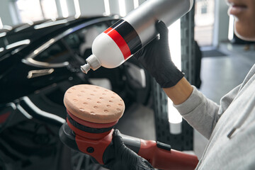 Professional detailer preparing electric buffer for car polishing