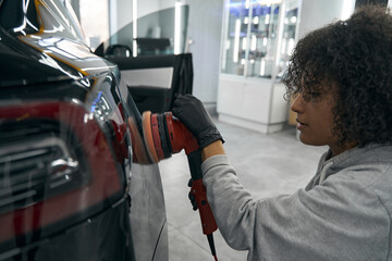 Concentrated car detailer buffing customer vehicle with orbital polisher