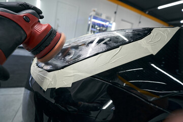 Gloved hand polishing headlamp with car buffer © Viacheslav Yakobchuk