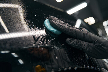 Service station worker preparing car paintwork for polishing