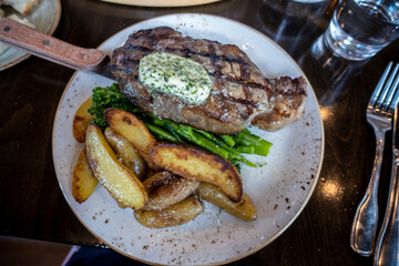 Top down view of a delectable steak frites dinner on a wooden table inside a restaurant