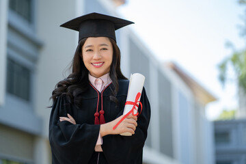 Graduated students on graduation day. She stood with her arms crossed and held her diploma in hand.