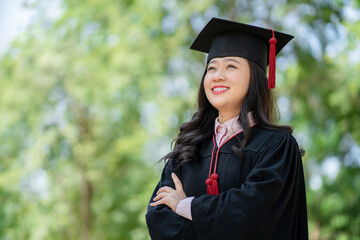 Woman wearing graduation gown in university campus.