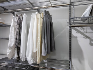 Collection of monotone colors tops and bottoms hanging inside an organized walk in closet with...