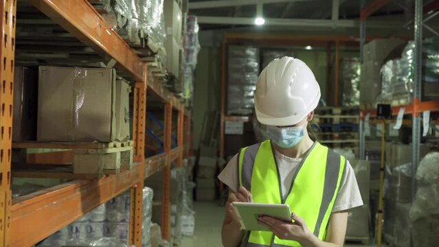 A female supervisor wearing a safety vest, hard hat, and face mask during an inspection at a factory