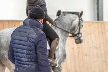 Fototapete Rund Reiten A riding instructor give lessons to an equestrian on a horse in a riding hall  © Annabell Gsödl