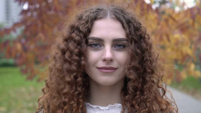 Portrait of a young woman with brown hair and green eyes on an autumn background. Beautiful woman in autumn park