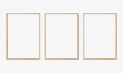 Photo frame mockup. Set of three vertical oak wooden frames on white wall. Template for artwork, painting or poster.
