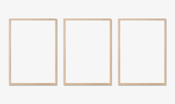 Photo frame mockup. Set of three vertical oak wooden frames on white wall. Template for artwork, painting or poster.