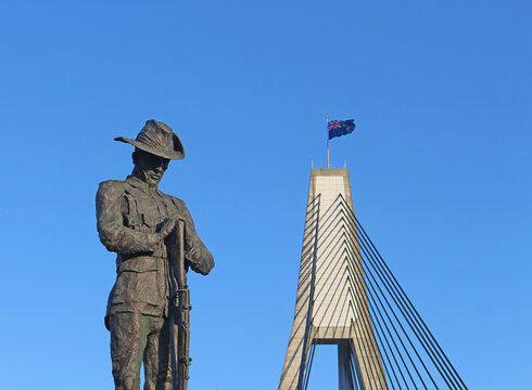 Bronze statue of an Australian World War One Digger. The statue of the New Zealand soldier. Blue sky and the Anzac Bridge in the background. Remembrance Day. Sydney