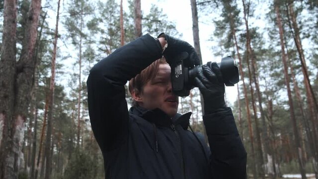 A photographer takes pictures in the woods, a young man takes pictures in the woods with his camera. Beautiful nature through the eyes of a photographer. . High quality 4k footage