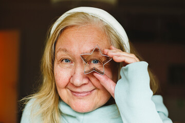 Senior woman looking through star shaped cookie cutter