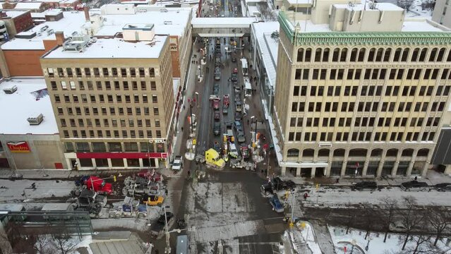 Large trucks from the freedom convoy block multiple intersections in Ottawa's snowy city center to protest mandatory vaccination. Drone tilt dolley shot