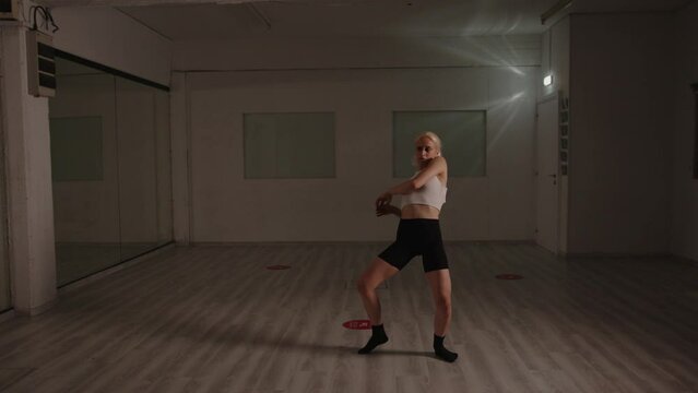 Beautiful woman passionately practicing dance routine alone in empty dance studio. Slow motion medium shot