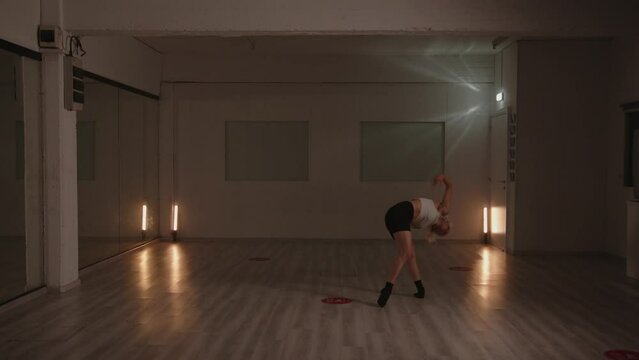 Girl contemporary dancer elegantly performing in empty dance studio. Slow motion