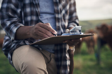 Dont work against nature, work with it. Shot of an unrecognisable man writing notes while working on a cow farm.