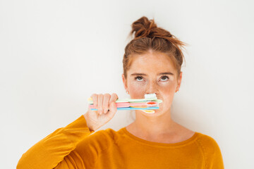 Woman holding toothbrushes against white background