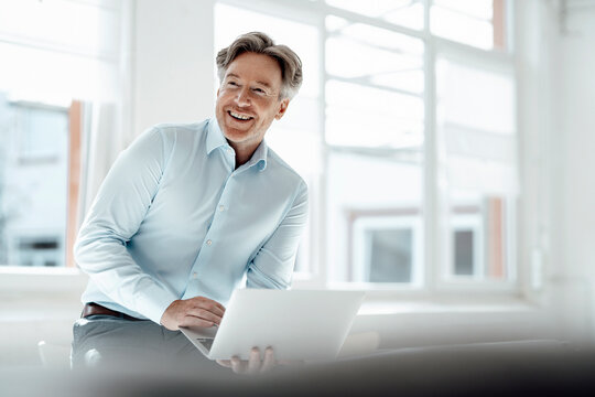 Smiling businessman with laptop in office