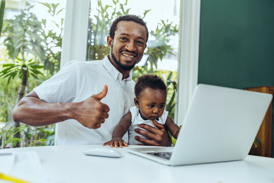 Happy businessman doing thumbs up by laptop at home
