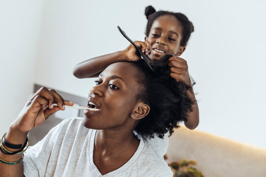 Daughter doing hair of mother in bathroom