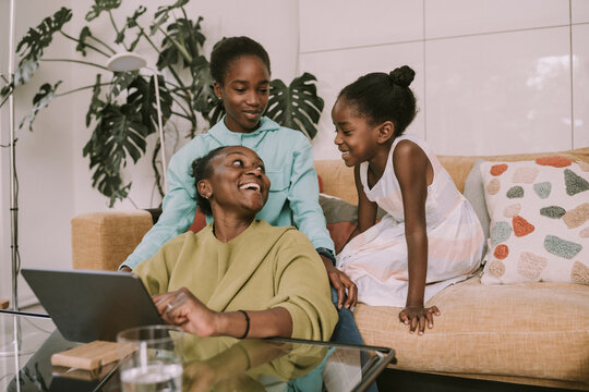 Happy mother talking with daughters in living room