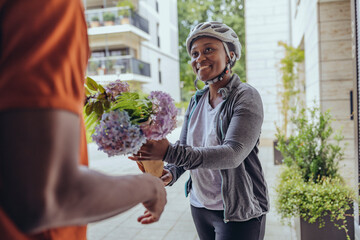 Smiling delivery woman giving flower bouquet to man at doorway