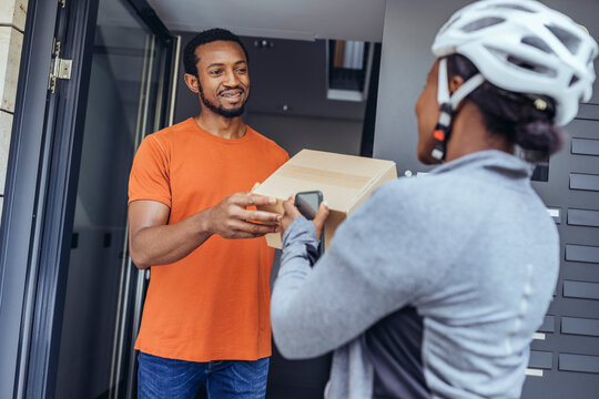 Customer receiving package box from delivery woman at doorway