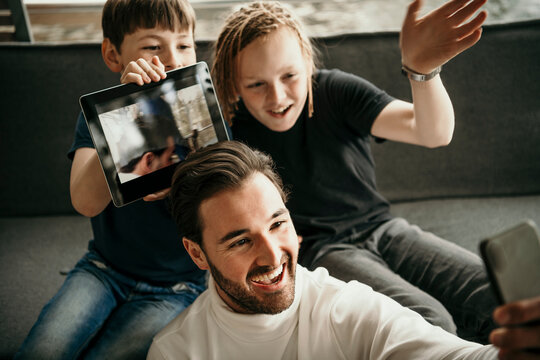 Happy man with sons taking selfie through mobile phone at home