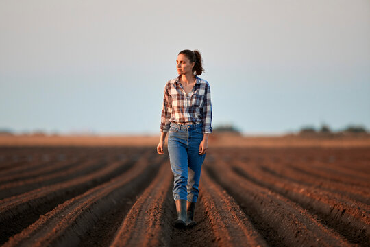 Young farmer walking in field at sunset