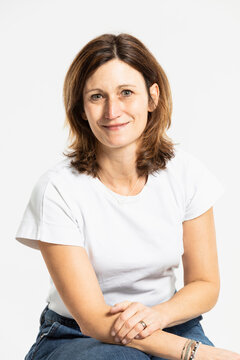 Smiling woman sitting against white background in studio