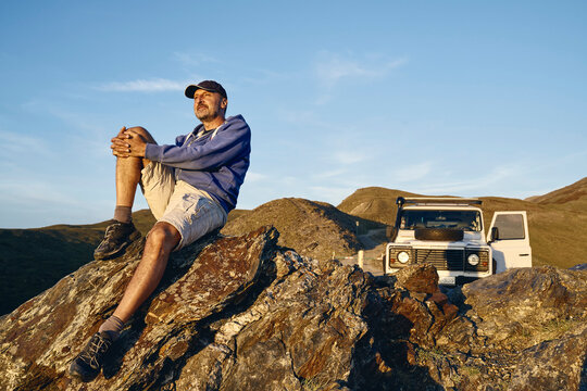 Contemplative man sitting on rock at vacation, Colle dell'Assietta, Turin, Italy