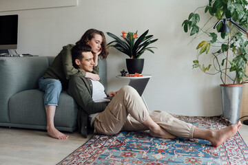 Young couple sharing laptop in living room at home