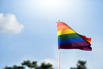 Rainbow flag, a symbol for the LGBT community, waving in the wind with a cloudy bluesky background. 