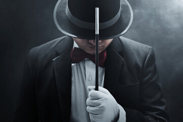 Magician holding magic wand on dark background