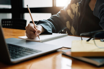 Cropped photo of asian woman writing making list taking notes in notepad working or learning on...