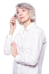 An attractive elderly woman listens very attentively to the interlocutor during a telephone conversation using a smartphone isolated on white background