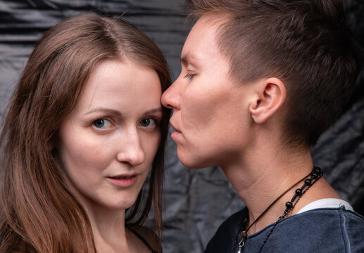 Photo of two kissing homosexual women on dark background