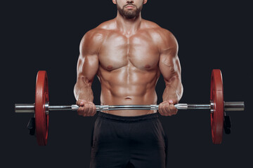 Close up of strong bodybuilder muscular arms lifting a barbell isolated on black background