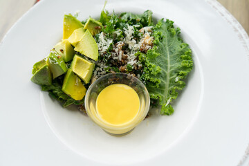 Avocado and Curl leaf kale with lettuce vegetable and Salad dressing that healthy food in white plate at restaurant.
