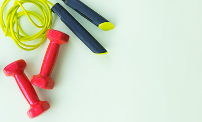 Red dumbbells and jump rope on a light background