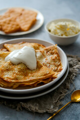 Pancakes on a plate with sour cream, golden spoon