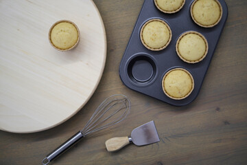 Fresh baked homemade muffins in baking dish on a wooden table. Close up, horizontal view from above