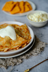 Pancakes on a plate with sour cream, golden spoon