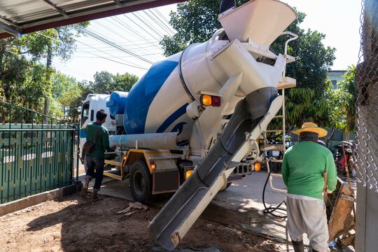 Workers pouring concrete with a cement mixer truck.