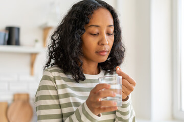 African-american female washing down pill with glass of water.Healthy supplement remedy treatment