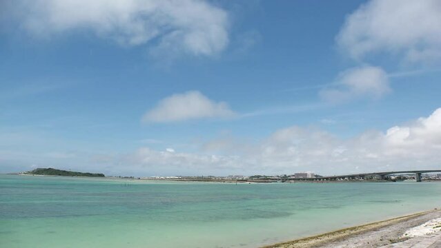TOMIGUSUKU, OKINAWA, JAPAN - AUGUST 2021 : View of Senaga island and beach (Ocean or sea) in daytime. Clear blue summer sky and clouds. Holiday, vacation and resort concept video. Time lapse shot.