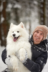 A human and a dog are best friends. Man and dog walk in snowy forest in winter in deep snow on a sunny day.