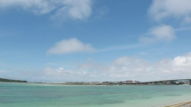 TOMIGUSUKU, OKINAWA, JAPAN - AUGUST 2021 : View of Senaga island and beach (Ocean or sea) in daytime. Clear blue summer sky and clouds. Holiday, vacation and resort concept video. Time lapse shot.