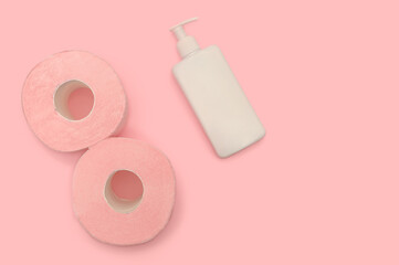 Pink toilet paper on a pink background and lotion. Health and hygiene every day.