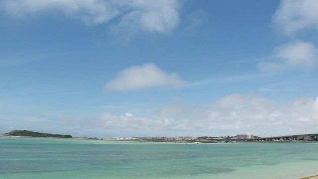 TOMIGUSUKU, OKINAWA, JAPAN - AUGUST 2021 : View of Senaga island and beach (Ocean or sea) in daytime. Clear blue summer sky and clouds. Holiday, vacation and resort concept video. Time lapse shot.